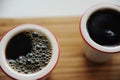 Fresh black filter coffee in two ceramic cups without handle on bamboo tray. White background. Top view, close up Royalty Free Stock Photo