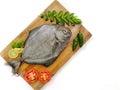 Fresh Black Pomfret Fish decorated with herbs and vegetables on a wooden pad Selective focus Royalty Free Stock Photo