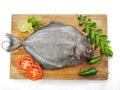 Fresh Black Pomfret Fish decorated with herbs and vegetables on a wooden pad Selective focus Royalty Free Stock Photo