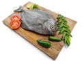 Fresh Black Pomfret Fish decorated with herbs and vegetables on a wooden pad Selective focus Royalty Free Stock Photo