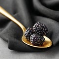 Fresh blackberries on a golden spoon against black fabric. Royalty Free Stock Photo