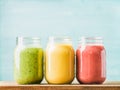 Fresh blended fruit smoothies of various colors and tastes in glass jars. Green, yellow, red.