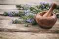 Fresh blooming rosemary and a mortar on a wooden table, copy space