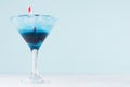 Fresh blue alcohol cocktail with ice cubes, red straw in misted wineglass on green color background, white wood board. Royalty Free Stock Photo