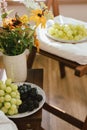 Fresh blueberries, blackberries and grapes in sunlight and wildflowers bouquet in rustic room. Summer berries in light, healthy