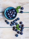 Fresh blueberries in blue bowl and leaves of mint on white wooden table Royalty Free Stock Photo