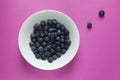 Fresh blueberries in a bowl on pink background.