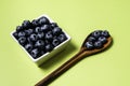 Fresh blueberries inside pot on green background and wooden spoon Royalty Free Stock Photo