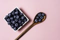 Fresh blueberries inside pot on pink background and wooden spoon Royalty Free Stock Photo