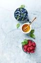 Fresh Blueberries and Raspberries with Honey and Mint Leaves on gray marble background. Flat lay. Healthy Diet Concept. Royalty Free Stock Photo