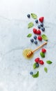Fresh Blueberries and Raspberries with Honey and Mint Leaves on gray marble background. Flat lay. Healthy Diet Concept. Royalty Free Stock Photo