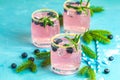 Fresh blueberry cocktail with rosemary and ice in glasses with decorate brown sugar on turquoise surface and black background. Royalty Free Stock Photo