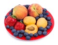 Fresh blueberry, strawberry, peach and apricot on a red plate Royalty Free Stock Photo