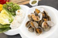 Fresh boiled cockle on white bowl dish eat with fresh vegetables rice noodle and spicy chili thai sauce on wood table Royalty Free Stock Photo