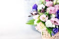 A fresh bouquet of multi-colored roses in a wicker basket stands on a white-gray background. Royalty Free Stock Photo