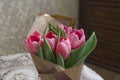 Fresh bouquet of pink tulips wrapped in papper at home interior.