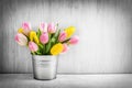 Fresh bouquet of tulips in a metal pot on rustic wood.