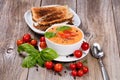 Fresh bowl of creamy tomato soup and sandwich with basil leaves