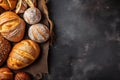 Fresh bread, buns, loaves, rolls on rustic black wooden background, top view, text copy space