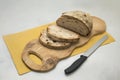 Fresh bread with crispy crust on wooden cutting board partially sliced. Knife and orange napkin. Fresh Sliced sourdough bread loaf