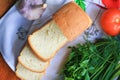 Fresh bread with cut pieces on a napkin, herbs and garlic, top view Royalty Free Stock Photo