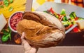 Fresh bread in hand of customer near supermarket wall