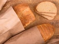 Fresh bread and loaf packaging in kraft paper on a wooden board background, top view