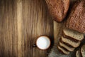 fresh bread with a mug of milk on a cutting board and a burlap napkin on a wooden background. top view. Artistic rustic concept