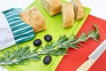Fresh bread, sprig of rosemary and olives on cutting board Royalty Free Stock Photo