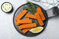 Fresh breaded fish fingers, sauce and lemon served on light grey table, flat lay Royalty Free Stock Photo