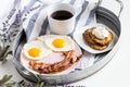 Fresh breakfast with bacons, eggs, a cup of coffee, and pancakes with cream on the tray