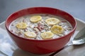 Fresh breakfast of granola, yogurt, nuts, goji berries, chia seeds and banana. Muesli with fruits and berries in red bowl Royalty Free Stock Photo