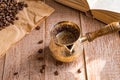 Fresh breved coffe in  cezve traditional turkish coffee pot opened book and coffee beans on wooden table Royalty Free Stock Photo