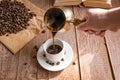 Fresh breved coffe in cezve traditional turkish coffee pot Woman`s hand pours coffee into white cup