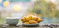 Fresh brewed coffee in white cup or mug on windowsill. Coffee drink with croissant dessert. Enjoying coffee on rainy day Royalty Free Stock Photo