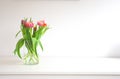 Fresh bright bouquet of colorful Tulips near white wall on wooden shelf in glass vase wit space for text, Spring, April Royalty Free Stock Photo