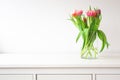 Fresh bright bouquet of colorful Tulips near white wall on wooden shelf in glass vase wit space for text, Spring, April Royalty Free Stock Photo