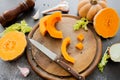 Fresh bright cutted pumpkin on a wooden chopping board with knife. Celery and garlic, onions and scattered peppercorns and salt