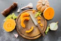 Fresh bright cutted pumpkin on a wooden chopping board with knife. Celery and garlic, onions and scattered peppercorns and salt