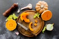 Fresh bright cutted pumpkin on a wooden chopping board with a knife. Celery and garlic, onions and scattered peppercorns and salt