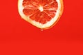 Fresh bright grapefruit with water drops on red background, copy space. Royalty Free Stock Photo