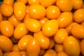 Fresh bright plum-shaped orange tomatoes in bulk. Vegetables, fruits