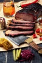 Fresh Brisket BBQ beef sliced for serving against a kraft paper background with sauce, hot peppers and corn.