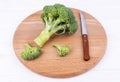 Broccoli lies next to a knife on a wooden board