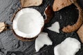 Fresh broken coconut half on black slate background.