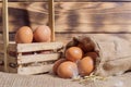 Fresh brown chicken eggs in a basket on a sacking on wooden background. Easter holidays background Royalty Free Stock Photo