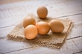 Fresh brown eggs on burlap cloth on white plank wood background, Easter, simplicity