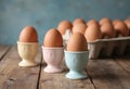 Fresh brown eggs in pastel egg cups on a rustic wooden table Royalty Free Stock Photo