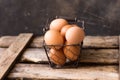 Fresh brown eggs in a wire basket on a vintage wood box, black background, Easter, decoration