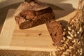 Fresh, brown, freshly baked, multi-grain and yeast-free bread on a cutting board and cereals, cut off a piece of the Royalty Free Stock Photo